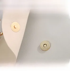 Detailed close-up of the polished golden magnetic snap closure on a grey cartoon bag