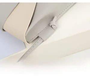 Macro detail of precision stitching on gray and beige two-tone leather crossbody bag
