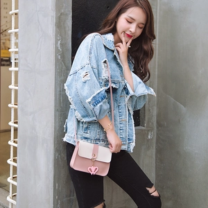 Crossbody phone bag in pink and beige with heart charm over light blue denim jacket