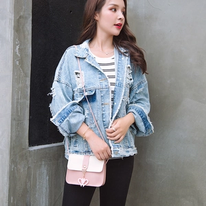 Detail of pink and white crossbody bag with heart pendant and metal buckle on model