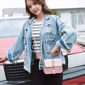 Pink and white crossbody bag with double heart charms worn by a model in the city