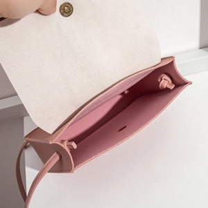 Detail of light pink pebble leather crossbody bag showing magnetic snap and suede lining