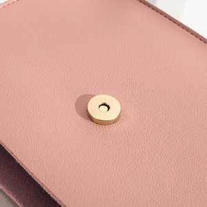 Close-up of pink textured leather bag with gold magnetic snap button and neat stitching