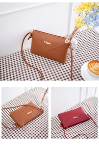 Detail of envelope crossbody bag with metal logo and leaf-shaped zipper pull charms