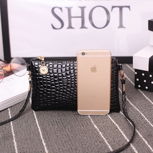 Glossy black crocodile pattern crossbody bag with round gold zipper pull and smartphone size guide