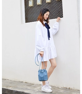 Detail of light blue leather drawstring bucket bag with beaded closure on a female model