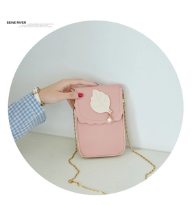 Détail du sac bandoulière rose pour téléphone avec breloque feuille, perle et chaîne
