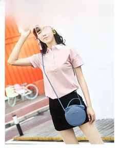 Outdoor model show of a round blue crossbody bag with lychee texture and gold logo