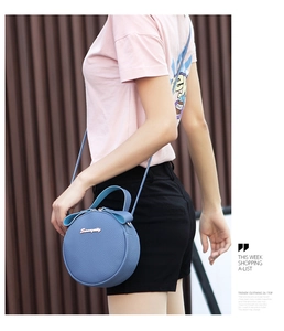 On-model shot of a blue round crossbody bag with litchi grain texture and gold logo