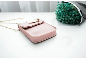 Gros plan détaillé du mini sac téléphone rose avec chaîne dorée et pendentif feuille