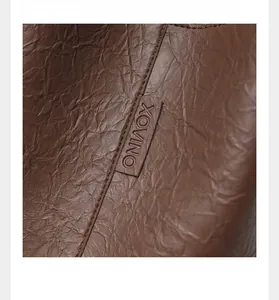 Close-up of pleated dark brown leather texture with XOVINO stitched logo detail
