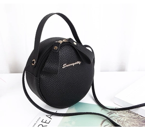 Detail of round black crossbody bag in lychee pattern PU leather with gold dual zippers