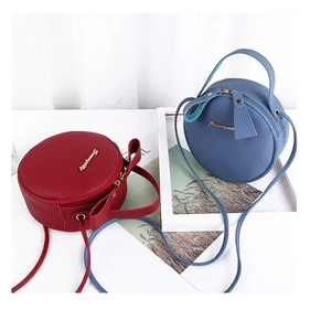 Detail of red and blue round crossbody bags with gold logo and lychee grain leather