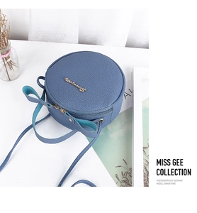 Detail of blue lychee grain leather mini bag with bow handle and golden zipper hardware