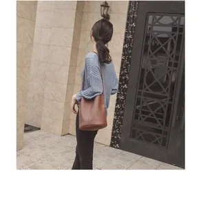 Outdoor lifestyle shot of a brown textured leather bucket bag with slim shoulder strap