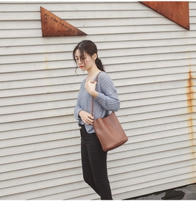 Close-up of brown vintage bucket bag with litchi texture on a female model outdoors