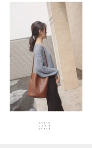 Close-up of brown textured leather bucket bag with embossed logo and shoulder strap