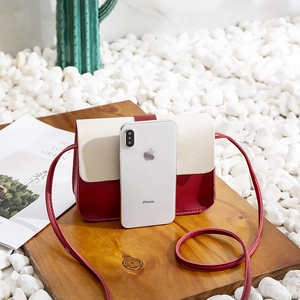 Crossbody mini phone bag in wine red and cream pebble leather on a wooden surface