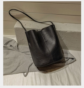Detail of black bucket bag with natural wrinkled texture and elegant shoulder strap