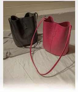 Close-up of black and magenta crinkled leather bucket bags with fine vertical stitching