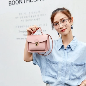 Elegant pale pink mini crossbody bag with gold metal clasp and adjustable shoulder strap