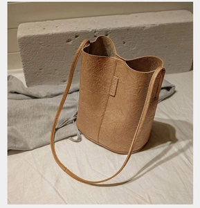 Detail view of the brown leather bucket bag with textured surface and brand tag