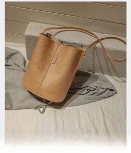 Detail of light brown bucket bag featuring unique pleated texture and thin shoulder strap