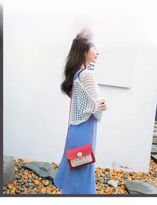 Détail du sac rouge et beige avec motifs ajourés et fermoir doré rond élégant
