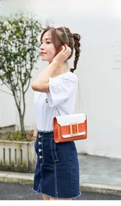 Vue détaillée du sac contrasté orange tendance avec boucle dorée porté par un modèle