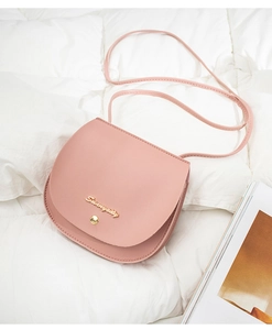 Detailed view of a pink PU leather saddle bag with gold metal logo on a quilted background