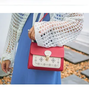 Détail du sac bandoulière rouge et crème avec motifs ajourés au laser et fermoir