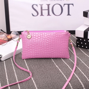 Pink croc-effect crossbody bag with gold-tone zipper charm and slim shoulder strap