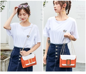 Détail du sac à bandoulière en cuir orange et blanc avec boucle carrée dorée iconique