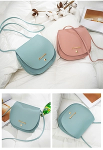 Detail of light blue and pink saddle crossbody bags with metal buckle on white bedding