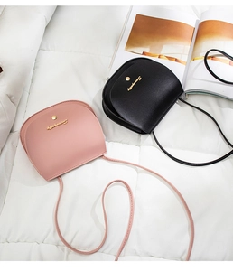 Flat lay of black and pink saddle crossbody bags with gold hardware on white background