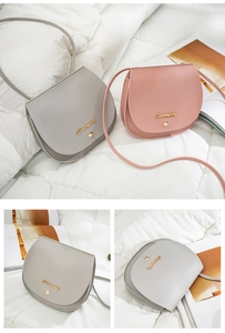 Detail view of stylish matte leather saddle bags in light grey and pink with gold logo