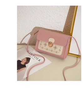 Détail du sac bandoulière rose et beige avec motifs floraux évidés et boucle métallique