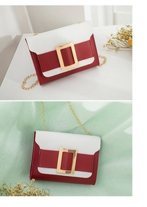 Détail du sac bicolore rouge et blanc avec grande boucle dorée et bandoulière chaîne