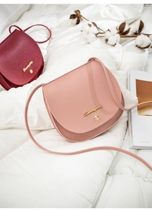 Pink and wine red saddle bags made of textured leather on a soft white background