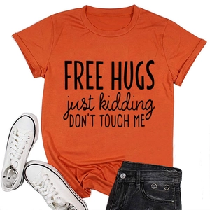 Detailed flat lay of bright orange cotton t-shirt with Free Hugs slogan and black denim shorts