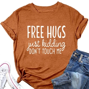 Flat lay of terracotta 'FREE HUGS' t-shirt with blue jeans and white sneakers