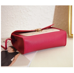 Détail du sac bandoulière avec motifs ajourés magenta et fermoir rotatif doré élégant