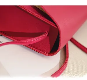 Détail de la fixation de la bandoulière fine cachée sur un sac en cuir rose fuchsia
