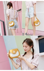 Detailed close-up of contrasting saddle bag with teardrop metal lock and thin strap