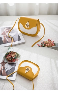 Detail of yellow and white saddle bag featuring a golden teardrop-shaped metal lock