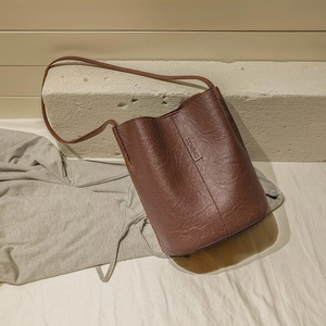 Retro brown bucket bag with textured leather and XOVINO logo in a premium lifestyle setting