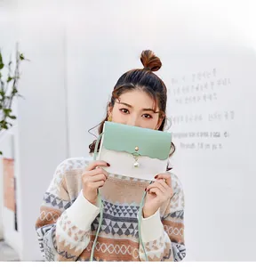 Detail of mint green and ivory crossbody bag with wave edges and a pearl pendant charm