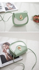 Detail of light green saddle bag showing gold teardrop metal buckle and leather texture