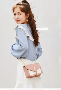 Chic pink and cream crossbody bag featuring a golden cat head clasp with long fringe tassels