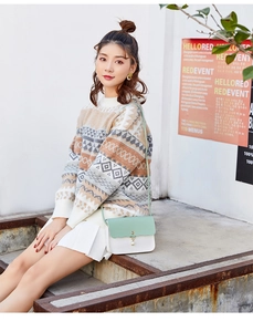 Outdoor shot of a contrast color crossbody bag with pearl pendant on a knit sweater outfit